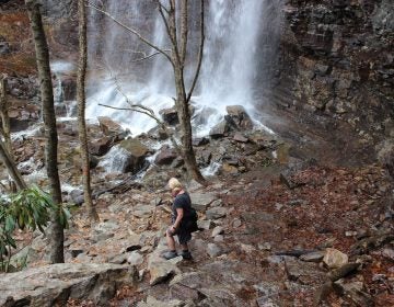 An unidentified woman makes her way to the base of a waterfall