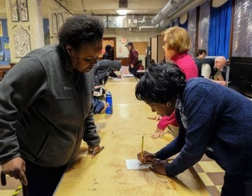 Dee McDowell (left), who is experiencing homelessness, collects her mail from volunteer Chris Martin at Broad Street Ministry on Avenue of the Arts. (Anthony Pezzoti/The Philadelphia Inquirer)