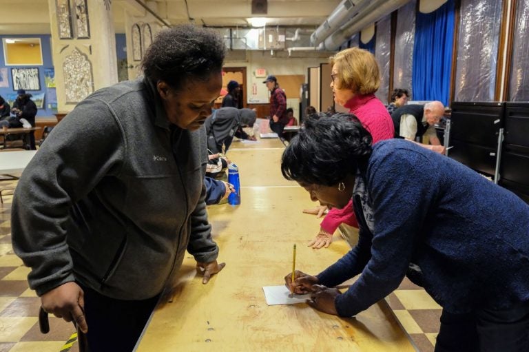 Dee McDowell (left), who is experiencing homelessness, collects her mail from volunteer Chris Martin at Broad Street Ministry on Avenue of the Arts. (Anthony Pezzoti/The Philadelphia Inquirer)