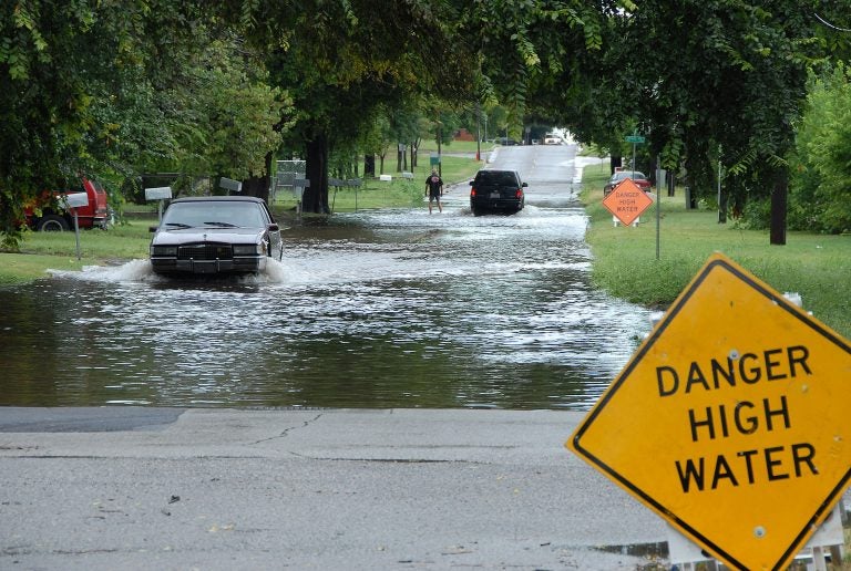 Car driving through a flooded street. (FEMA)