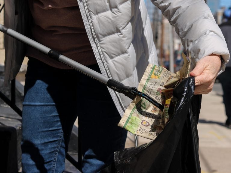 Amanda Bauman picks off litter on her block every week in Point Breeze. Circulars like the one she stuffs in her black garbage bag, are her biggest pet peeve. (Angela Gervasi for WHYY)