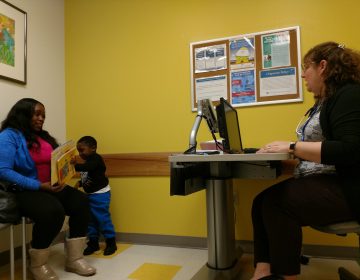 Pediatrician Eileen Everly and mom Teneika Thomas discuss Kyiren Smith's literacy progress during the 4-year-old's visit. Thomas said the boy corrected his teacher when she skipped two pages of a book she was reading in class. (Christine Bahls for WHYY)
