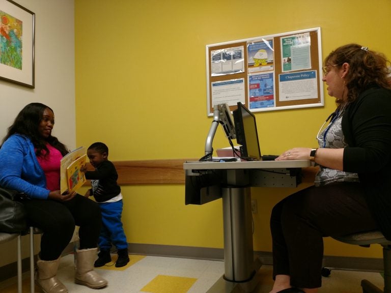 Pediatrician Eileen Everly and mom Teneika Thomas discuss Kyiren Smith's literacy progress during the 4-year-old's visit. Thomas said the boy corrected his teacher when she skipped two pages of a book she was reading in class. (Christine Bahls for WHYY)