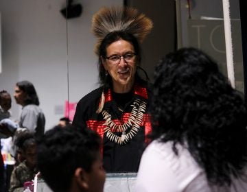 Tchin, an internationally showcased jewelry maker who lives in New Jersey, speaks with visitors at the We Are the Seeds festival (Angela Gervasi for WHYY)