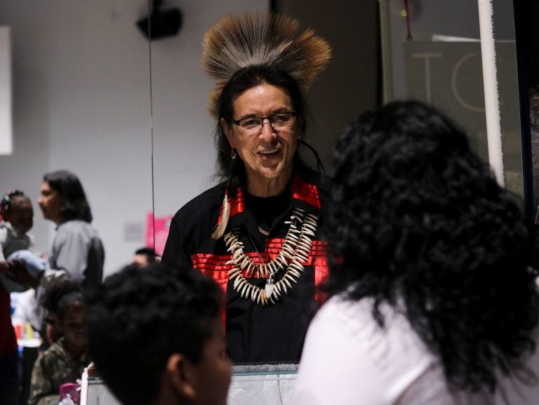 Tchin, an internationally showcased jewelry maker who lives in New Jersey, speaks with visitors at the We Are the Seeds festival (Angela Gervasi for WHYY)