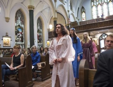  In the opening procession of “Via Crucis”, Jesus, portrayed by Marc Newsome, Mary, portrayed by Melanie Ashe, an the Weeping Women played by Miranda Pilate and Megan Short walk down the center aisle of St. John the Evangelist Church.   (Jonathan Wilson for WHYY)