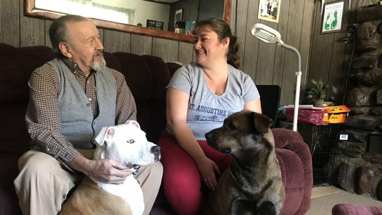 David Calderwood and Crystal Abel of Newport, Vt., sit with Abel's dogs Mike (left) and Zoe. David lives in Crystal's house, and she helps him with his medications and medical needs. He pays room and board, and Abel is also compensated by the state with Medicaid dollars.
(Emily Corwin/Vermont Public Radio)