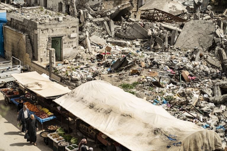 Customers walk near makeshift fruit and vegetable shops set in front of destroyed buildings in the northern Syrian city of Raqqa earlier this month. (Delil Souleiman /AFP/Getty Images)