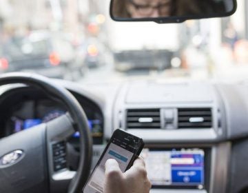 Philadelphia Uber driver consults her phone during a shift. (Jessica Kourkounis for WHYY)