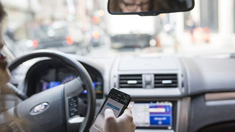 Philadelphia Uber driver consults her phone during a shift. (Jessica Kourkounis for WHYY)