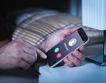 Unknown number calling in the middle of the night. Phone call from stranger. Person holding mobile and smartphone in bedroom bed home late. Unexpected call woke up.