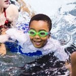 Natalie Edman (left), a freshman at the University of Pennsylvania, gives Quintin Whitner, 6 (center), a swimming lesson through We Can Swim on March 23, 2019. (Rachel Wisniewski for WHYY)