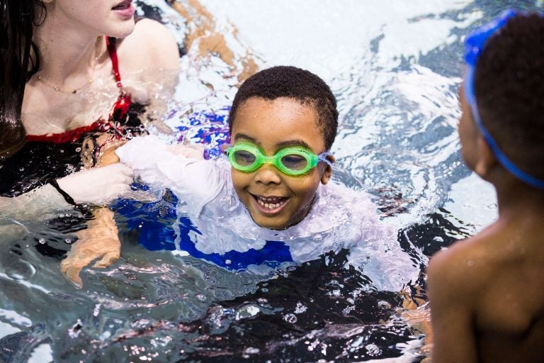 Natalie Edman (left), a freshman at the University of Pennsylvania, gives Quintin Whitner, 6 (center), a swimming lesson through We Can Swim on March 23, 2019. (Rachel Wisniewski for WHYY)