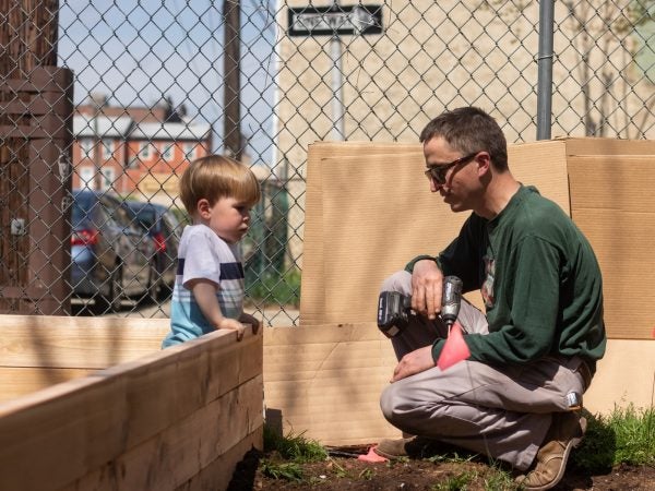 Clifford Brown (right), a former volunteer with La Finquita, stops to chat with Sam Prasak as the new community garden progresses. (Angela Gervasi for WHYY)