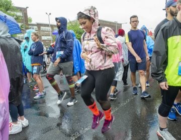 While waiting for the Broad Street Run to begin, Alba Miranda warms up near the Olney Transportation Center. Miranda is a member of the running group Latinas in Motion. (Jonathan Wilson for WHYY)