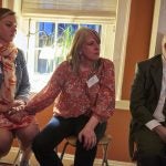 Izzy Harper holds her mother, Cara Moser's hand during the Friends of Safehouse event after Moser shares her experience of losing her daughter to addiction a few months prior. They both sit beside Jose Benitez, President of Safehouse and Executive Director of Prevention Point Philadelphia. (Natalie Piserchio for WHYY)