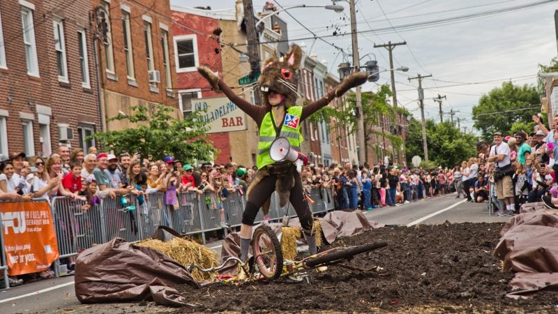 CB, lead costume designer for the Crazy Bike Clan, celebrates by throwing mud in the air. (Kimberly Paynter/WHYY)