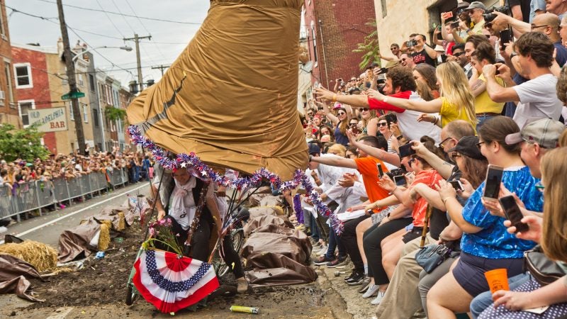 The crowd lends a hand holding up a liberty bell as it failed to get through the Kensington Kinetic Sculpture Derby mud pit. (Kimberly Paynter/WHYY)