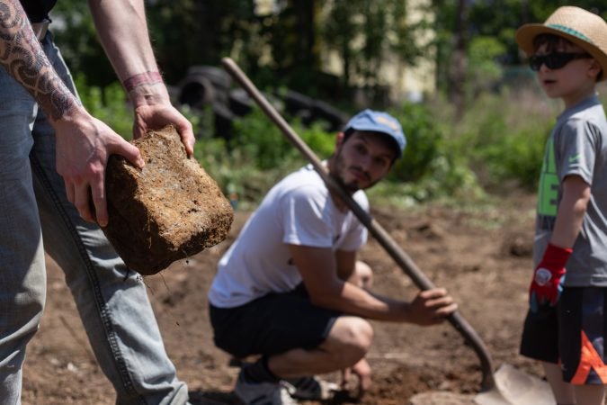 Volunteers dig bricks and stones out of the ground in order to clear land for the César Andreu Iglesias Community Garden. (Angela Gervasi for WHYY)