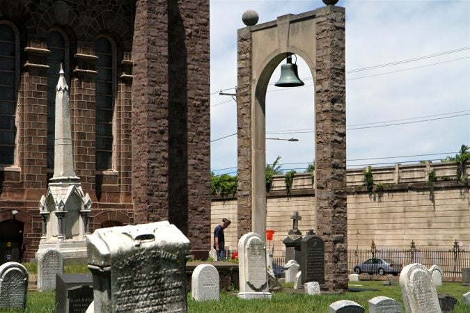 José Rivera pauses at the grave of a veteran in St. Anne's Cemetery in North Philadelphia. (Ximena Conde/WHYY)