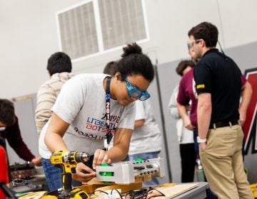 Ashley Yates of Harry S. Truman High School works on her team's robot between rounds at the Liberty Bots competition Saturday at Montgomery County Community College. (Brad Larrison for WHYY)