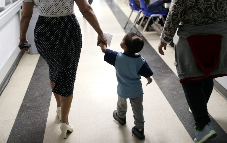 In this Friday, Jan. 11, 2019, photo, Maria Orbelina Cortez, (right), walks with her 3-year-old son, Julio, (center), and a worker at the Catholic Charities shelter in McAllen, Texas. Orbelina says she decided to flee El Salvador after her husband attacked her and caused a pan of hot oil to fall, scalding Julio and leaving a scar on his head. (Eric Gay/AP Photo)