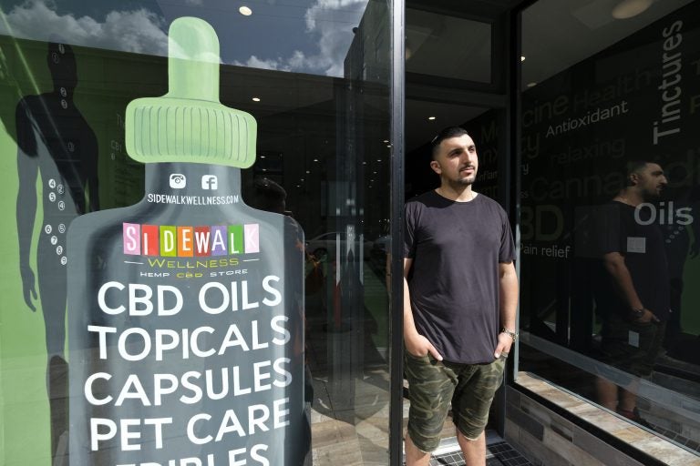 In this photo taken Thursday, March 21, 2019, Gus Dabais stands outside his Sidewalk Wellness store in San Francisco. CBD oil-infused food, drinks and dietary supplements are popular even though the U.S. government says they're illegal and some local authorities have forced retailers to pull products. The confusion has California, Texas and other states moving to legalize the cannabis compound that many see as beneficial to their health. (Eric Risberg/AP Photo)