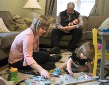 Christina Paravecchia, plays with daughter Madelyn Rose as her dad, Albert “Two-pops” Catarro helps out by holding baby Amelia Grace who was born March 20. Christina had half her brain removed in 1996, when she was eight-years-old. (William Johnson/The Intelligencer via AP)