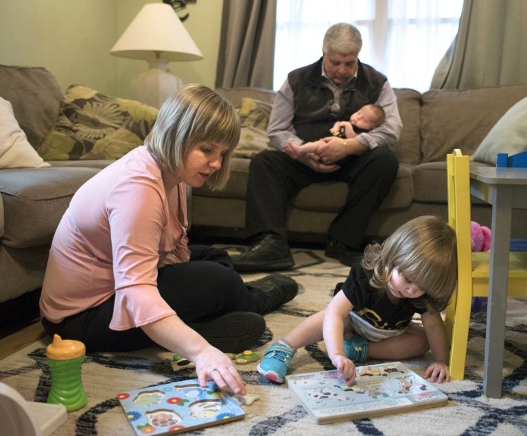 Christina Paravecchia, plays with daughter Madelyn Rose as her dad, Albert “Two-pops” Catarro helps out by holding baby Amelia Grace who was born March 20. Christina had half her brain removed in 1996, when she was eight-years-old. (William Johnson/The Intelligencer via AP)