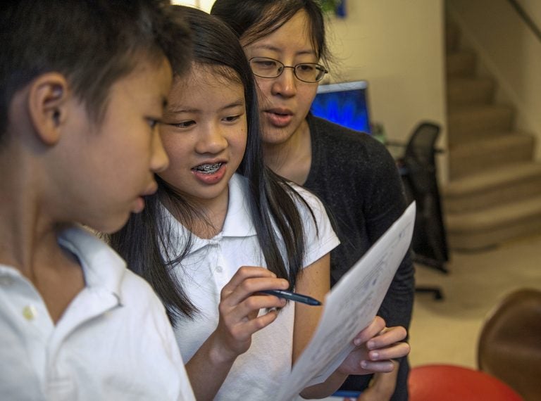 Vivian Loh, (center), a seventh grader at Winchester Thurston School and the first girl to win the Pennsylvania MATHCOUNTS competition, explains the solution to a math problem to her brother Vincent, 10, and their mother Debbie after they each completed a practice worksheet in the morning before school, Thursday, April 25, 2019, at their home in Squirrel Hill.  (Alexandra Wimley/Pittsburgh Post-Gazette via AP)