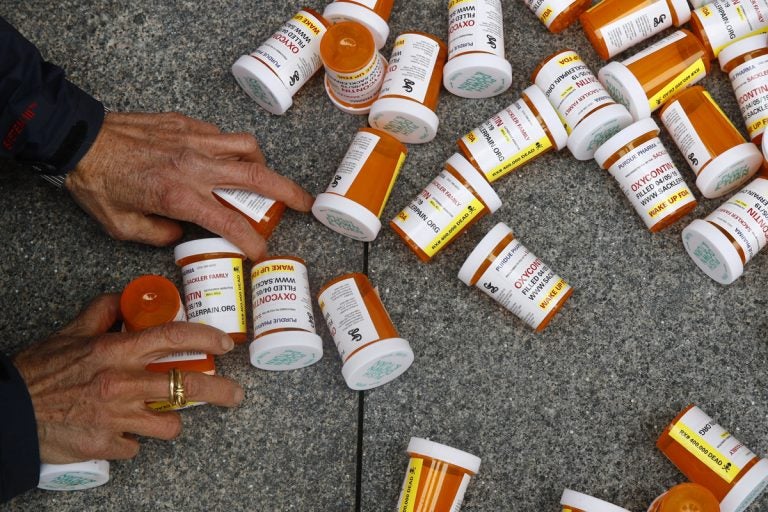 In this Friday, April 5, 2019, file photo, a protester gathers containers that look like OxyContin bottles at an anti-opioid demonstration in front of the U.S. Department of Health and Human Services headquarters in Washington, D.C. (Patrick Semansky/AP Photo)