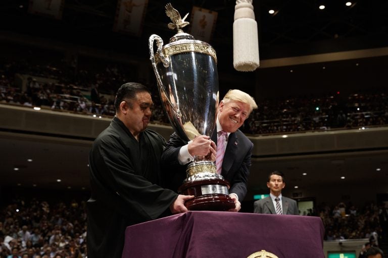 President Donald Trump picks up the 'President's Cup' to present to the Tokyo Grand Sumo Tournament winner Asanoyama, at Ryogoku Kokugikan Stadium, Sunday, May 26, 2019, in Tokyo. (Evan Vucci/AP Photo)