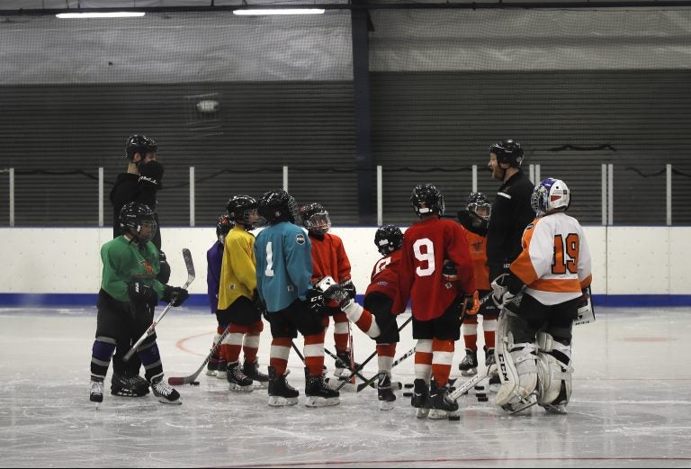 FILE - In this Feb. 21, 2019, file photo, Malakye Johnson (1) gathers with his teammates during a Snider Hockey practice at the Scanlon Ice Rink in Philadelphia. The Philadelphia-based Snider Hockey organization named after the late Flyers owner now has over 3,000 kids in its program and almost a third are girls. Snider Hockey officials want to get to a point that boys and girls are split 50-50, and a new endeavor with the Howe Foundation is another step toward that goal. (AP Photo/Matt Rourke, File)