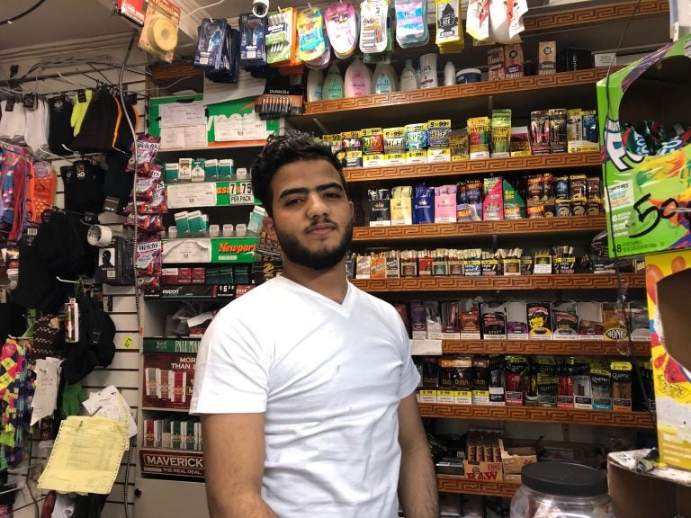 Nasraddin Asramat, who runs the cash register at Bill’s Deli Market, said crowds have thinned since the store resumed business. (Cris Barrish/WHYY)