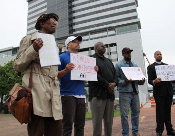 A small group of protesters gather outside Camden’s newest corporate high rise, demanding that beneficiaries of state tax breaks demonstrate what they’re doing to help Camden residents. (Emma Lee/WHYY)