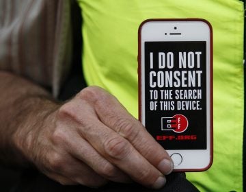 In this 2016 photo, a man holds up his iPhone during a rally in support of data privacy outside the Apple store in San Francisco. Watchdog groups that keep tabs on digital privacy rights are concerned that U.S. Customs and Border Protection agents are searching the phones and other digital devices of international travelers at border checkpoints in U.S. airports. (Eric Risberg/AP)