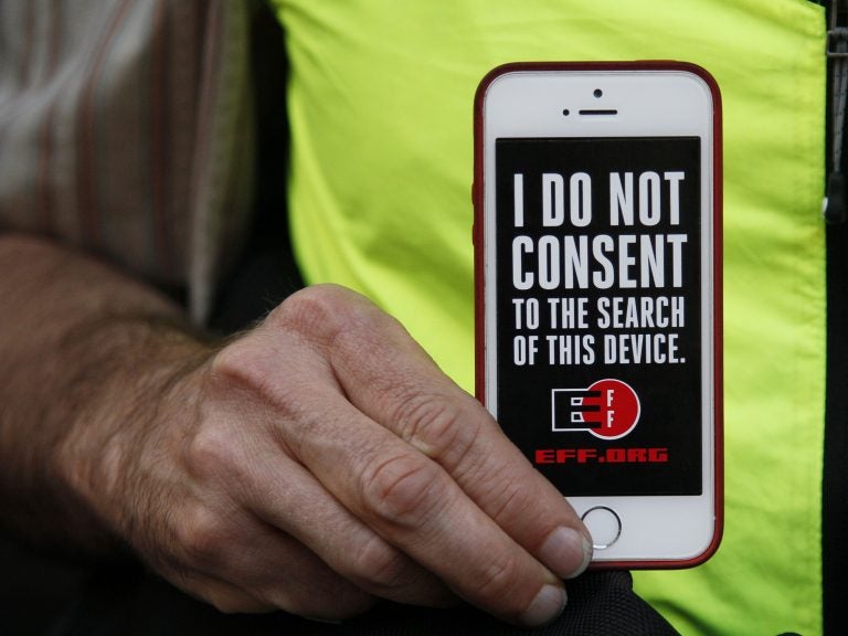 In this 2016 photo, a man holds up his iPhone during a rally in support of data privacy outside the Apple store in San Francisco. Watchdog groups that keep tabs on digital privacy rights are concerned that U.S. Customs and Border Protection agents are searching the phones and other digital devices of international travelers at border checkpoints in U.S. airports. (Eric Risberg/AP)