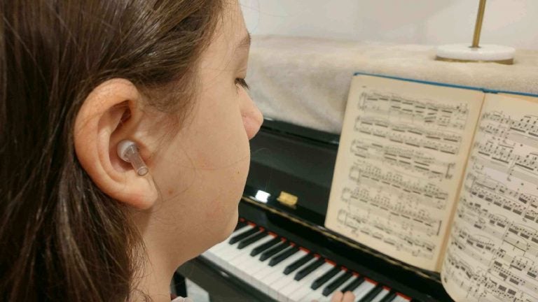 Theodore playing piano with ear protection (Randy Scott Carroll for WHYY)