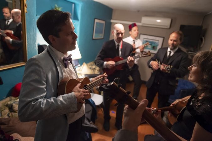 Members of the Philadelphia Ukulele Orchestra rehearse in their dressing room during intermission. (Jonathan Wilson for WHYY)