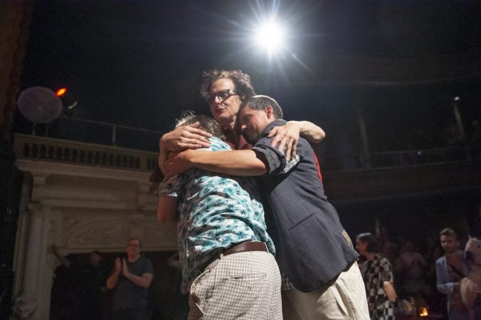 (From left) Greg Giovanni, Jimmy Mooney, and Sam Fulginiti embrace after the show. (Jonathan Wilson for WHYY)
