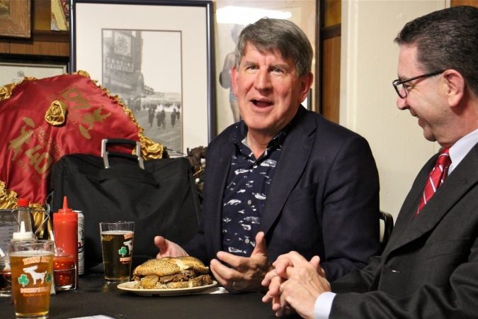 Anthony Bourdain's brother, Chris, sits down to a Donkey's cheesesteak with N.J. Assemblyman Paul Moriarity, who sponsored the resolution establishing the Anthony Bourdain Food Trail. (Emma Lee/WHYY)