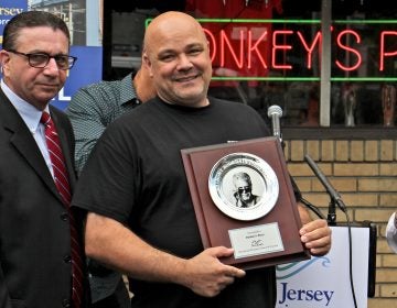 Rob Lucas, owner of Donkey's Place in Camden, holds a plaque that recognizes his restaurant's inclusion in the Anthony Bourdain Food Trail, which identifies ten New Jersey restaurants visited by the celebrity chef. (Emma Lee/WHYY)