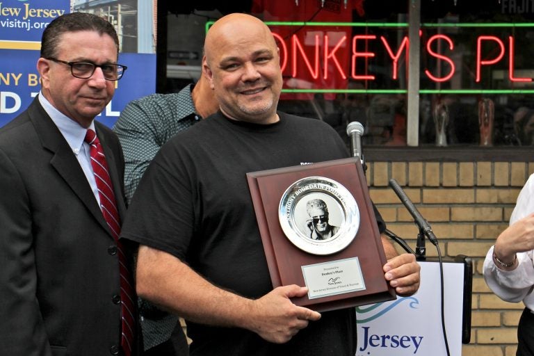 Rob Lucas, owner of Donkey's Place in Camden, holds a plaque that recognizes his restaurant's inclusion in the Anthony Bourdain Food Trail, which identifies ten New Jersey restaurants visited by the celebrity chef. (Emma Lee/WHYY)