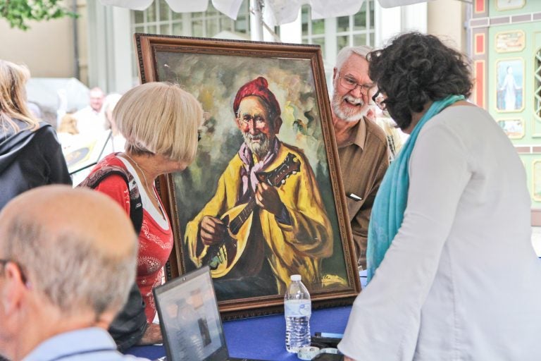 An appraiser examines a painting at the Antiques Roadshow taping at Winterthur. (Kimberly Paynter/WHYY)