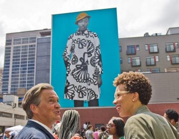 Realist painter Bo Bartlett talks with artist Amy Sherald (right) at the dedication of Sherald’s mural portrait of young Philadelphian, Najee Spencer-Young. (Kimberly Paynter/WHYY)