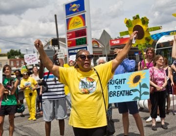 Sylvia Bennett, a member of Philly Thrive, raises her arms at a protest outside Philadelphia’s PES refinery. (Kimberly Paynter/WHYY)