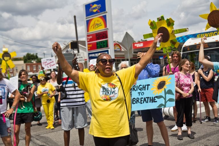 Sylvia Bennett, a member of Philly Thrive, raises her arms at a protest outside Philadelphia’s PES refinery. (Kimberly Paynter/WHYY)