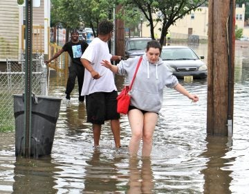 Westville residents (from right) Amberly Lynn, Jay Gray and Lamar Majette, wade through flood waters on Broadway. (Emma Lee/WHYY)