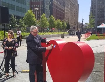 Mayor Jim Kenney puts his flag of family origin on the new sculpture at Love Park. (Tom MacDonald/WHYY)