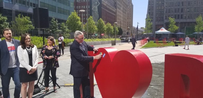 Mayor Jim Kenney puts his flag of family origin on the new sculpture at Love Park. (Tom MacDonald/WHYY)